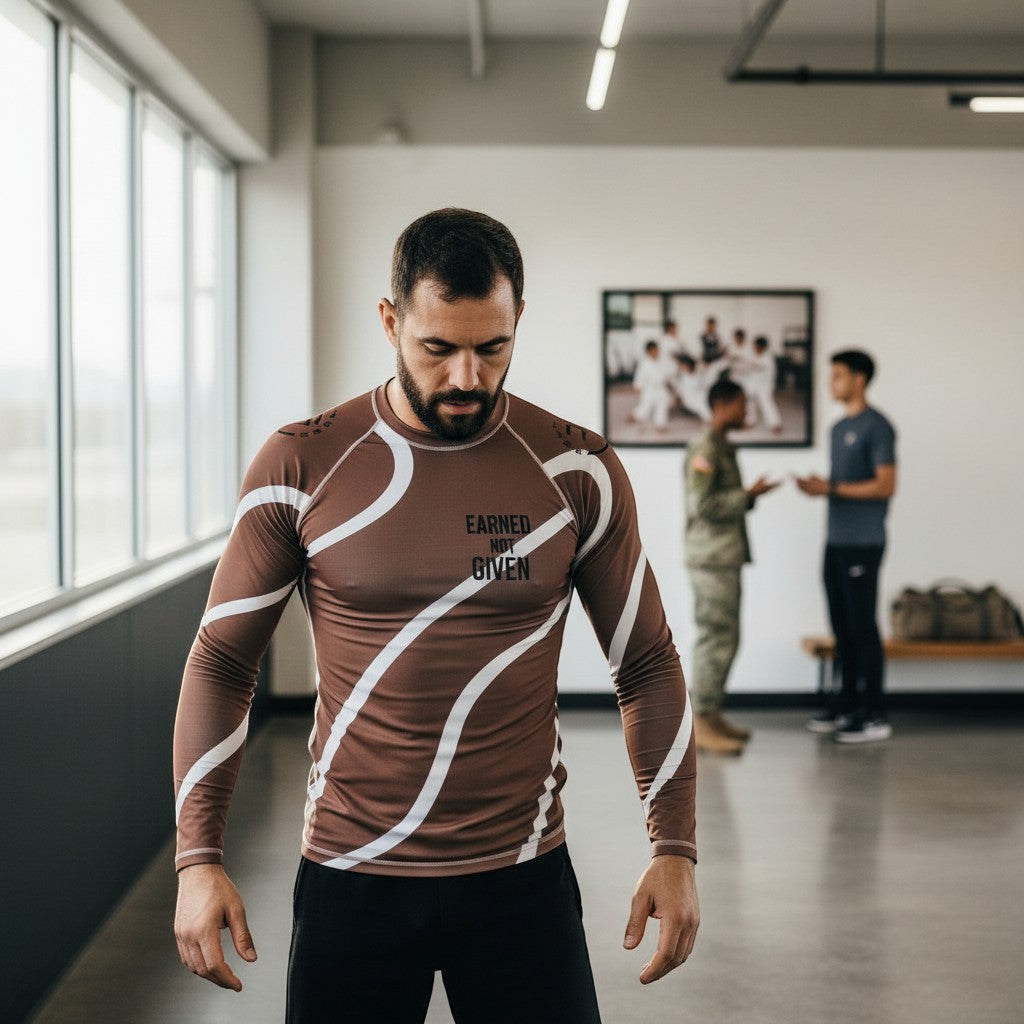 Roll Gear men's long-sleeve brown and white swirl rash guard with "Earned Not Given" text. Athletic fit.