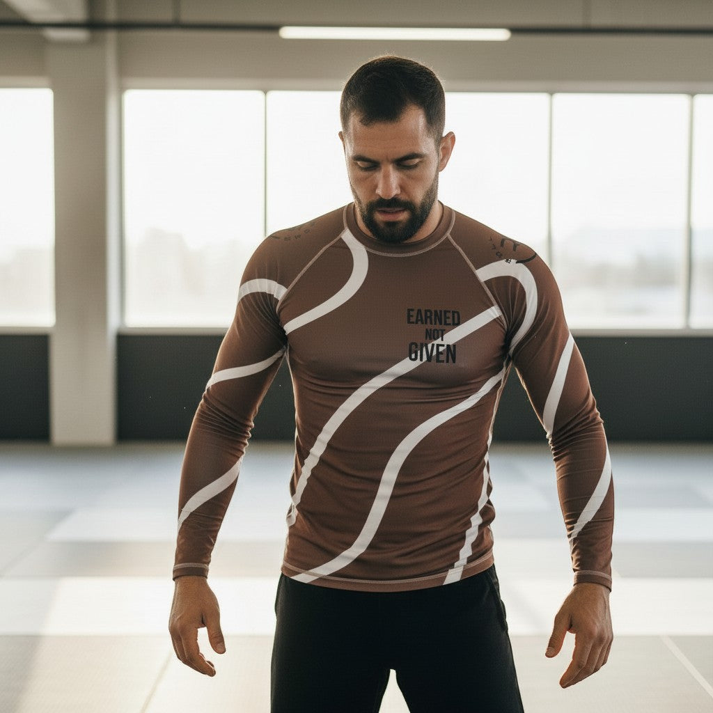 Roll Gear men's brown and white swirl long-sleeve rash guard with "Earned Not Given" text.
