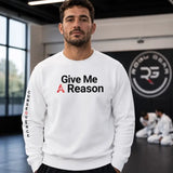 A man wearing a white crewneck sweatshirt with 'Give Me A Reason' printed on the chest and 'CONSEQUENCE' on the sleeve, standing in a martial arts studio.