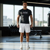 Roll Gear Earned Not Given Short Sleeve Rash Guard – Black, worn by a man standing in a gym.