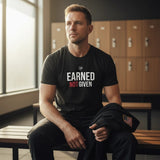 Roll Gear Earned Not Given black heavyweight cotton t-shirt with white and red graphic print on chest. Model sitting in locker room.