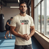 Roll Gear men's cream heavyweight cotton t-shirt with "EARNED NOT GIVEN" graphic on front. Model in gym.