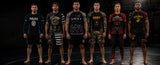 Six men standing side by side in a dark studio setting, each wearing a different graphic athletic rash guard and matching shorts. The shirts feature various designs including 'POLICE', 'SWAT', 'ARMY', and military-themed graphics such as 'USMC'.