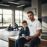 Man and child in jiu jitsu gis, the man wearing the white Jiu Jitsu Dad tee with the Full-Time Mat Analyst front print.