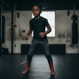 Roll Gear black compression spats for kids with red flame graphics, made of polyester and spandex for martial arts.