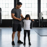 Roll Gear Kids Marines “Gold” compression spats in black with gold USMC graphics. Four-way stretch polyester-spandex blend.
