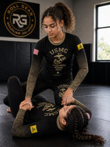 Roll Gear Kids Marines Gold military rash guard in black with faded gold sleeves and USMC emblem. Two girls training.