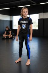 Roll Gear black compression spats for kids with blue thin line panels, police badge graphic, and four-way stretch fabric.