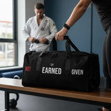 Roll Gear LLC black polyester duffel bag with "Earned Not Given" text, mesh side pocket, and dual handles.