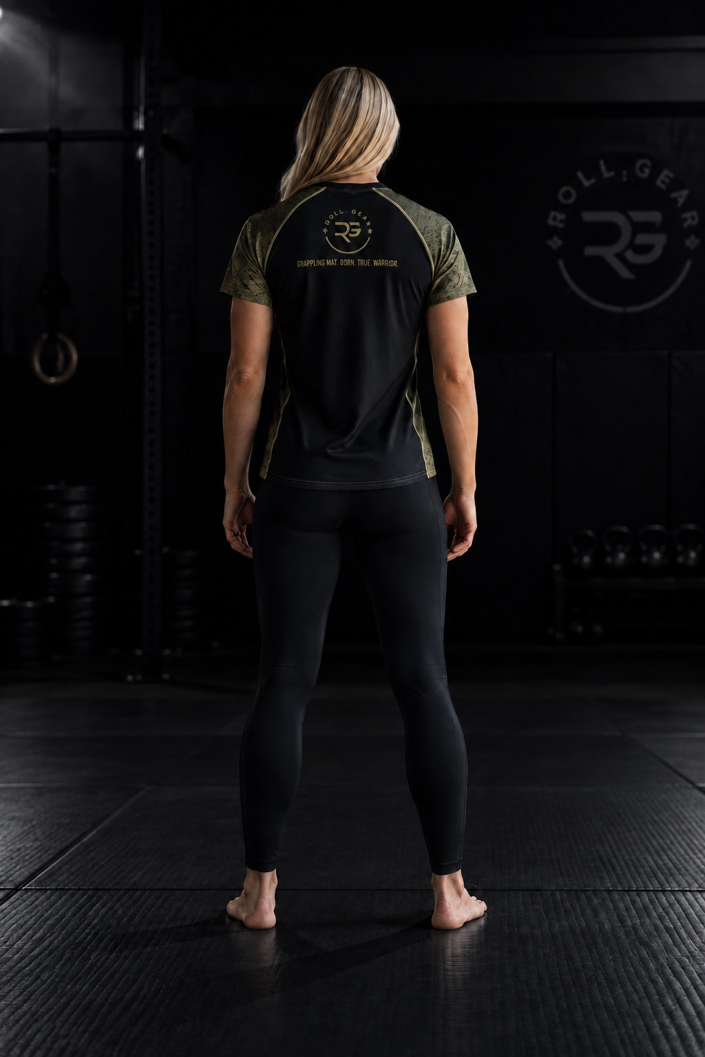 Roll Gear Unisex Marines Gold Short Sleeve Rash Guard, back view, worn by a female athlete with leggings.