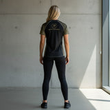 Roll Gear Unisex Marines Gold short sleeve rash guard in black with faded gold sleeves and gold emblem, worn by a woman.