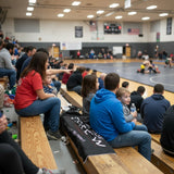 Roll Gear Mat Side Crew Sherpa Blanket in black with white text, draped over bleachers at a wrestling event.