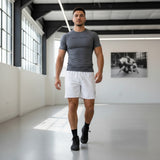 Roll Gear Mesh Shorts – All White – Unisex, worn by a man walking in a gym.
