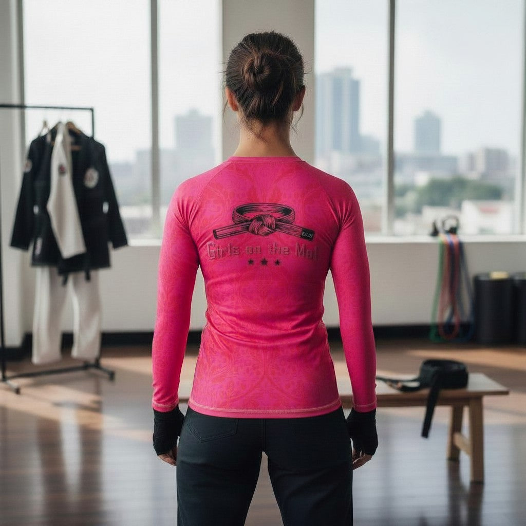 Roll Gear Earned Not Given Women's Long Sleeve BJJ Rash Guard, pink with a black belt graphic and Girls on the Mat text.