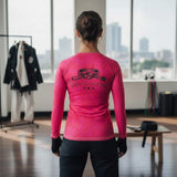 Roll Gear women's long sleeve rash guard in bright pink with a black belt graphic and "Girls on the Mat" text.