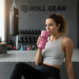 Roll Gear pink 20oz stainless steel tumbler with 'Girls on the Mat' logo, held by a woman in a gym.