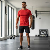 Roll Gear Performance Rash Guard – All Red Edition, worn by a man standing in a gym, front view.