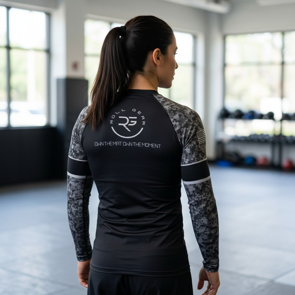 Roll Gear Women's SWAT Edition Long Sleeve Rash Guard, back view, Roll Gear emblem and urban camo sleeves, worn in the gym.