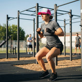 Roll Gear trucker hat with white front panel and hot pink mesh back, worn by a woman in athletic wear.