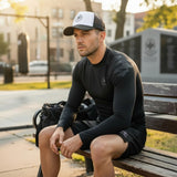 Roll Gear trucker hat with white front panel and black mesh back, worn by a man sitting on a bench.