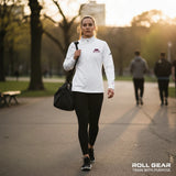 Roll Gear white polyester quarter-zip pullover with embroidered logo on chest and sleeve, worn by a woman walking outdoors.