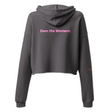 Roll Gear Women's dark grey cropped hoodie with "Own the Moment." printed in pink on the back.