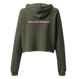 Roll Gear women's olive green cropped hoodie with pink text 'Own the Moment' on back.