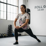 Roll Gear Athlete Edition women's short sleeve rash guard with a floral print in beige and pink. Fitted cut, moisture-wicking, UPF 50+.