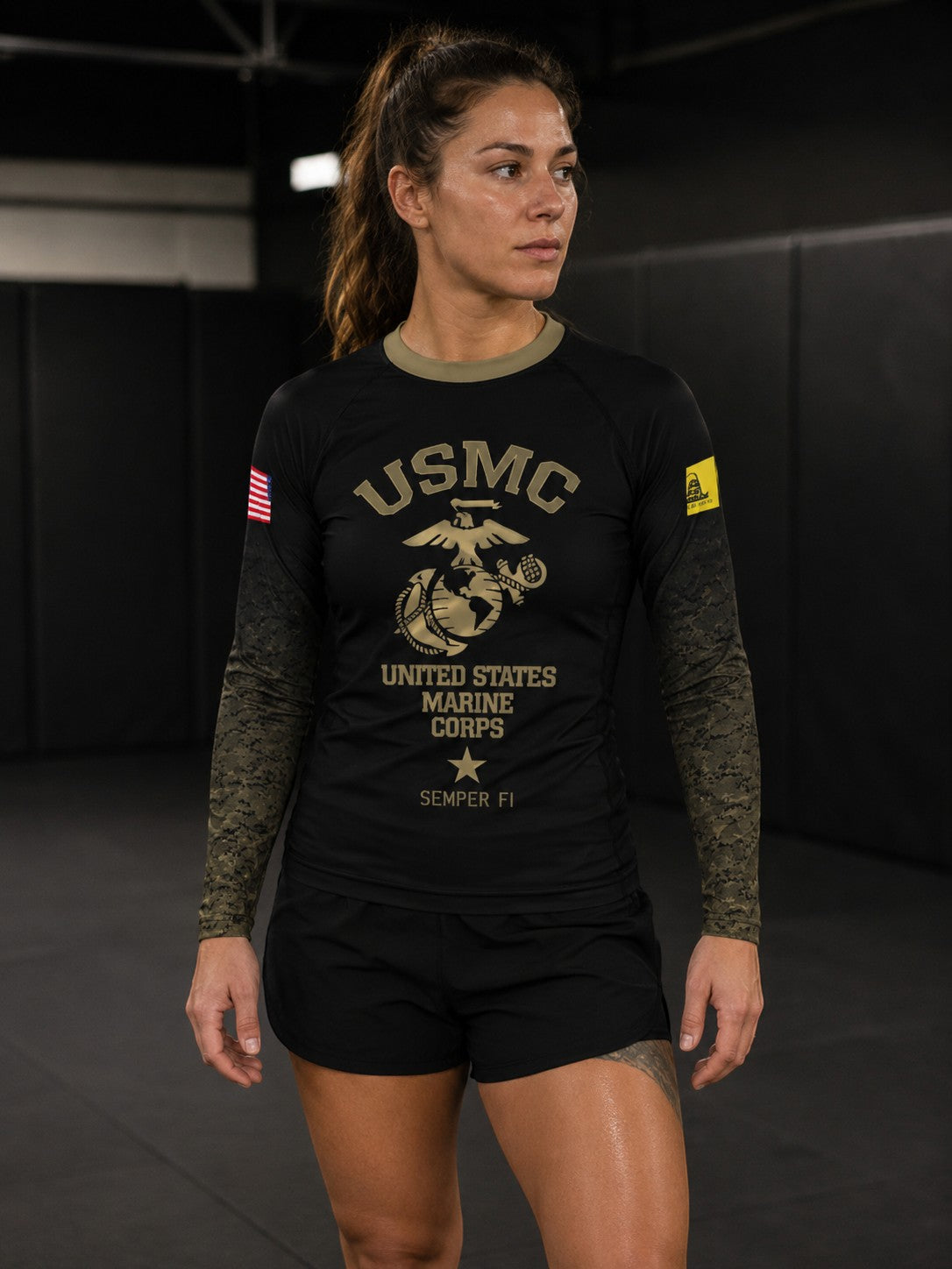 Roll Gear Women’s Marines “Gold” Military Rash Guard – Black & Faded Gold, worn by a woman standing on the mat.