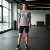Roll Gear youth grey t-shirt with "EARNED NOT GIVEN" graphic in red and white, worn by a boy in a gym.
