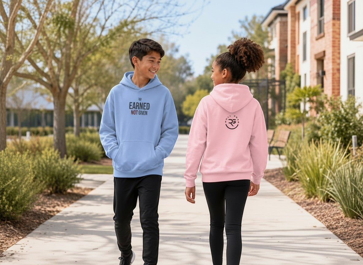Roll Gear youth heavyweight hoodie in light blue with "Earned Not Given" graphic on front. Model is a boy walking.