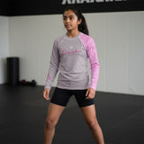 Roll Gear youth performance rash guard in grey with pink sleeves and graphic details. Long sleeve, crew neck, moisture-wicking fabric.