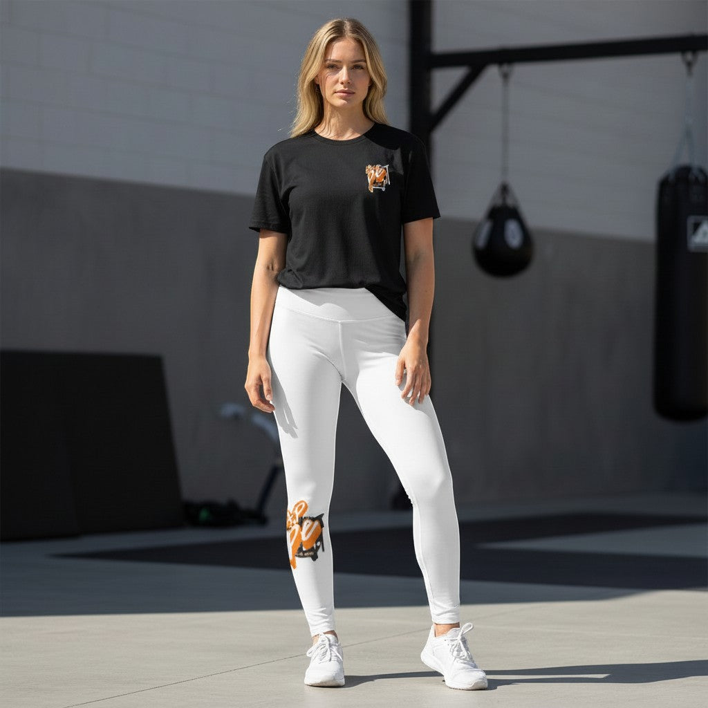 Roll Gear Tap Hype Youth BJJ Spats – Orange & White, worn by a model standing in a gym, front view.