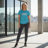 Roll Gear youth t-shirt in teal with "Earned Not Given" graphic, paired with dark grey joggers. Model is standing outdoors.