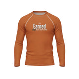 Roll Gear long sleeve rash guard in burnt orange with "Earned Not Given" graphic, side view. Moisture-wicking, 4-way stretch fabric for BJJ, wrestling, and MMA.