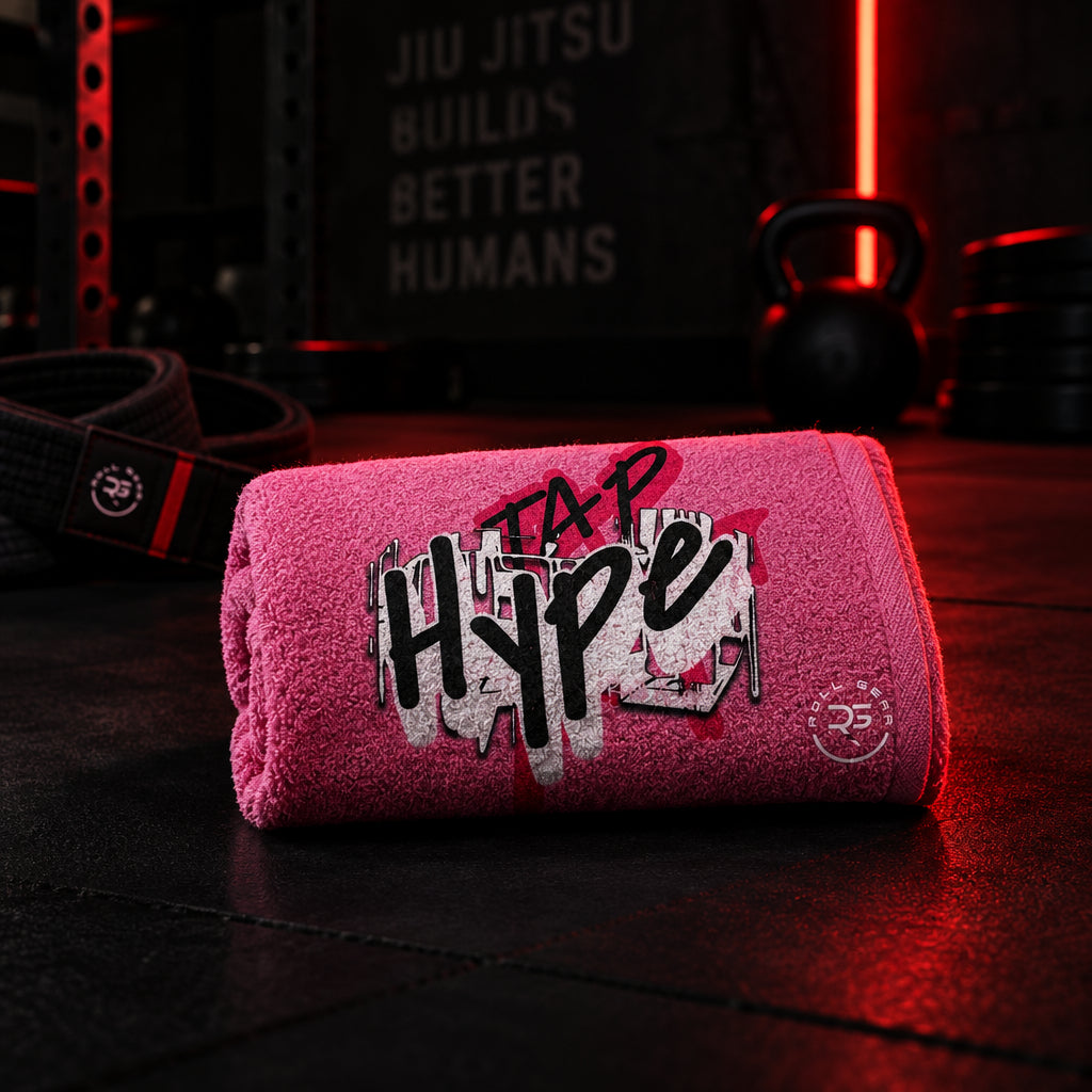 Roll Gear HYPE Training Towel in pink, folded towel on a gym bench.