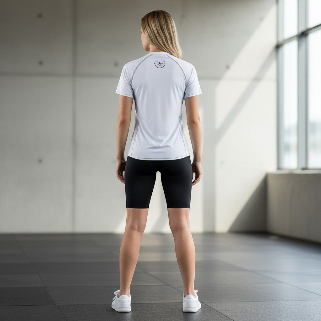 Roll Gear white short-sleeve performance rash guard with grey stitching and logo on back, worn by a woman.