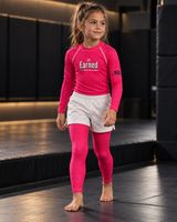 Roll Gear Earned Not Given Pink Rash Guard and Kids Spats, girl standing in the matching set, front view.